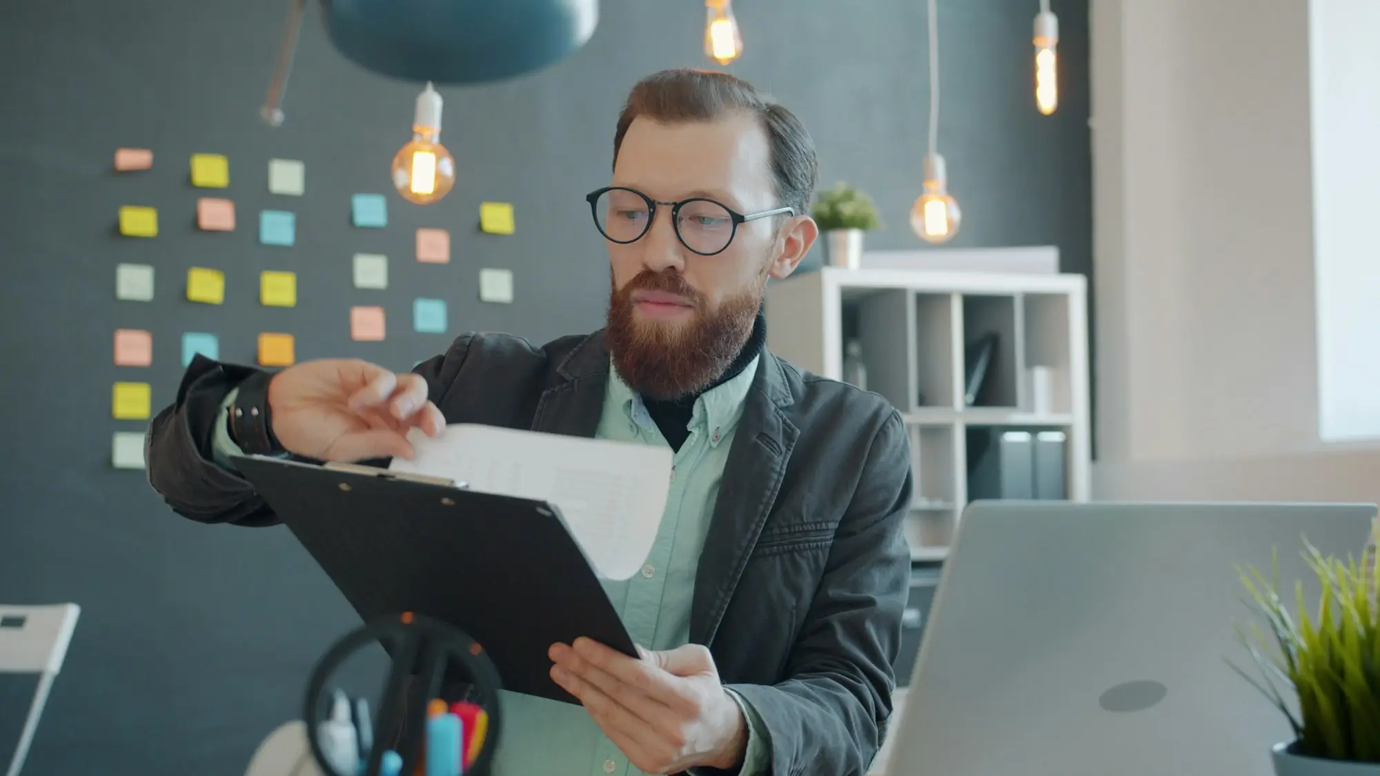 Man in glasses reviewing documents at his desk